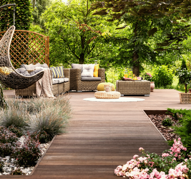Gemütliche Holzterrasse mit Lounge-Möbeln und Bepflanzung im Garten